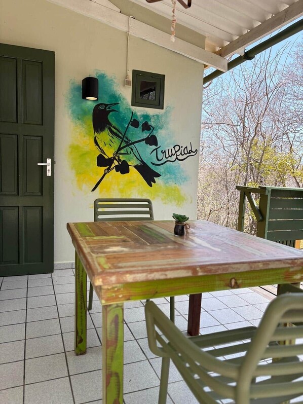 Un espace repas comprenant une table et des chaises, une peinture murale et une porte.
