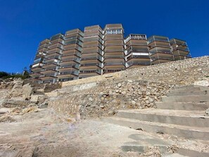 A multi-story building with balconies, situated on a rocky hillside. - Great Family Apartment with Lovely Sea Views · UHC PINOSMAR (Salou)