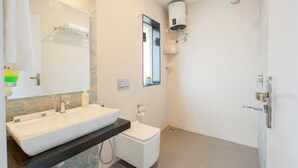 Et moderne badeværelse med stor vask, toilet og brusebad med vægmonteret varmelegeme.
