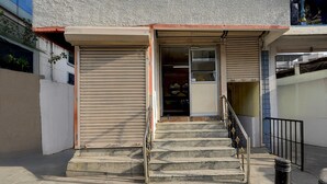 Um edifício com uma persiana fechada, uma escadaria que leva a uma entrada e um corrimão de metal.