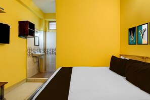 A hotel room with a bed, a bedside table, a mirror, a TV, and artwork on the wall. - Hotel O Egmore Formerly Harini Lodge (Chennai)