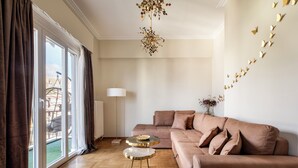 Ein Wohnzimmer mit Sofa, Couchtisch, Lampe und Blick durch ein großes Fenster.