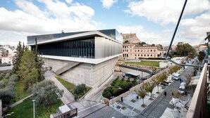 Ein modernes Gebäude mit Glasfassade, einem Innenhof und einem historischen Gebäude im Hintergrund.