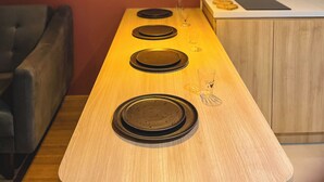A modern kitchen with a wooden countertop, a hanging pendant light, and a dark sofa. - Downtown Gramado-RS - With Free Parking - Vita Boulevard (Gramado)