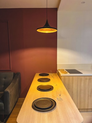 Uma cozinha moderna com bancada de madeira, luminária pendente e sofá escuro.