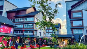 A modern building with multiple floors, a courtyard with a small water feature, and a variety of plants. - Downtown Gramado-RS - With Free Parking - Vita Boulevard (Gramado)