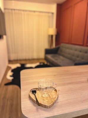 A wooden table with a glass mug and a spoon on a heart-shaped coaster. - Downtown Gramado-RS - With Free Parking - Vita Boulevard (Gramado)