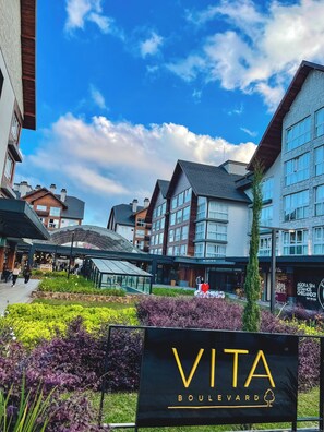 A commercial area with a sign for 'VITA BOULEVARD' and modern buildings with large windows. - Downtown Gramado-RS - With Free Parking - Vita Boulevard (Gramado)