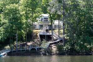 A lakeside property with a dock, a wooden deck, and a building with multiple levels. - Hot Tub! Hidden Kayak Cove -2 Masters, Kayaks, Fire pit, & Game Room (Jasper)