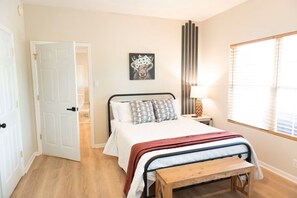 A bedroom with a bed, bedside table, lamp, and a window with blinds. - Hot Tub! Hidden Kayak Cove -2 Masters, Kayaks, Fire pit, & Game Room (Jasper)