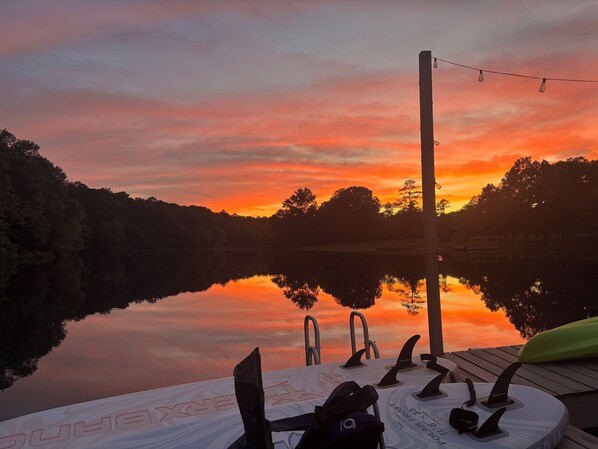 A sunset view over a calm lake with a dock and surfboards. - Hot Tub! Hidden Kayak Cove -2 Masters, Kayaks, Fire pit, & Game Room (Jasper)