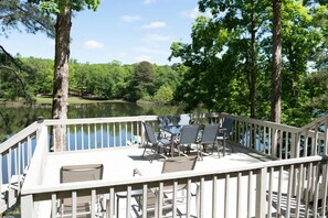 A deck with chairs and a table overlooking a lake, surrounded by trees. - Hot Tub! Hidden Kayak Cove -2 Masters, Kayaks, Fire pit, & Game Room (Jasper)