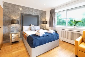 A modern bedroom with a large bed, bedside lamps, a window with a view, and a radiator. - Modern 5BR Retreat with Private Roof Terrace & Garden by Hyde Park (London)