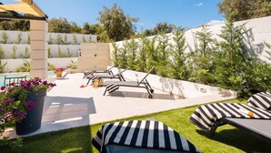 An outdoor patio with lounge chairs, a pergola, and a garden area with potted plants and a pool. - Villa Verde Razanj With Heated Pool (Rogoznica)