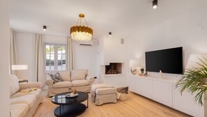 A modern living room with a sofa set, a coffee table, a TV, and a fireplace. - Villa Verde Razanj With Heated Pool (Rogoznica)