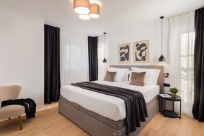 Um quarto moderno com uma cama grande, uma mesinha de cabeceira com uma planta e uma cadeira.