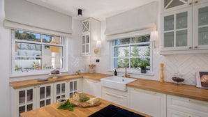 A modern kitchen with white cabinetry, a wooden countertop, a sink, and a window with a view of greenery. - Villa Verde Razanj With Heated Pool (Rogoznica)