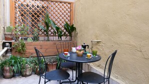 A small outdoor patio with a round table, four chairs, potted plants, and a wooden lattice fence. - Ernesta 3BR Lovely Home by The Spanish Steps (Roma)