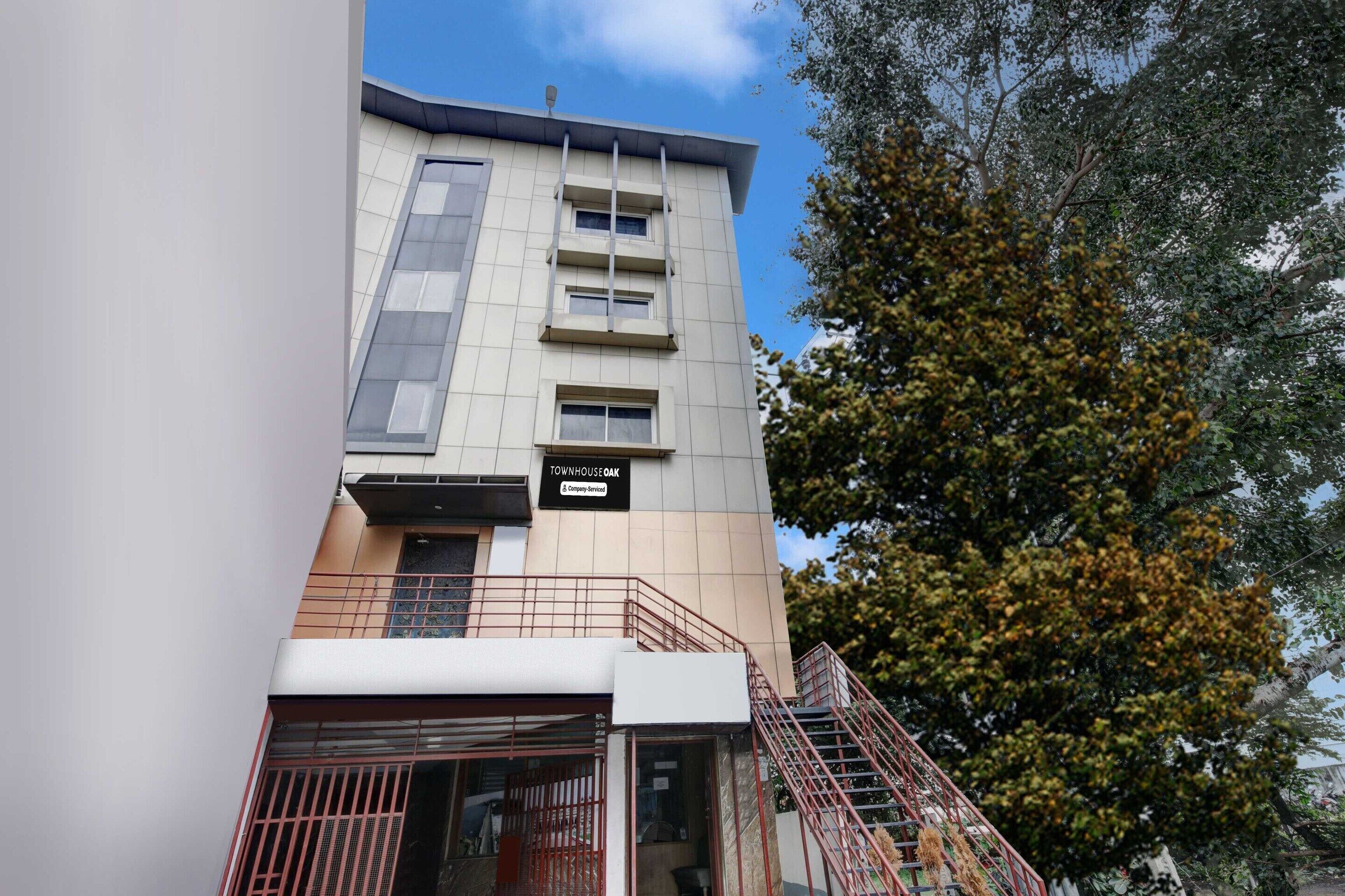 A multi-story building with a sign reading 'Townhouse Oak' and a staircase leading to the entrance.