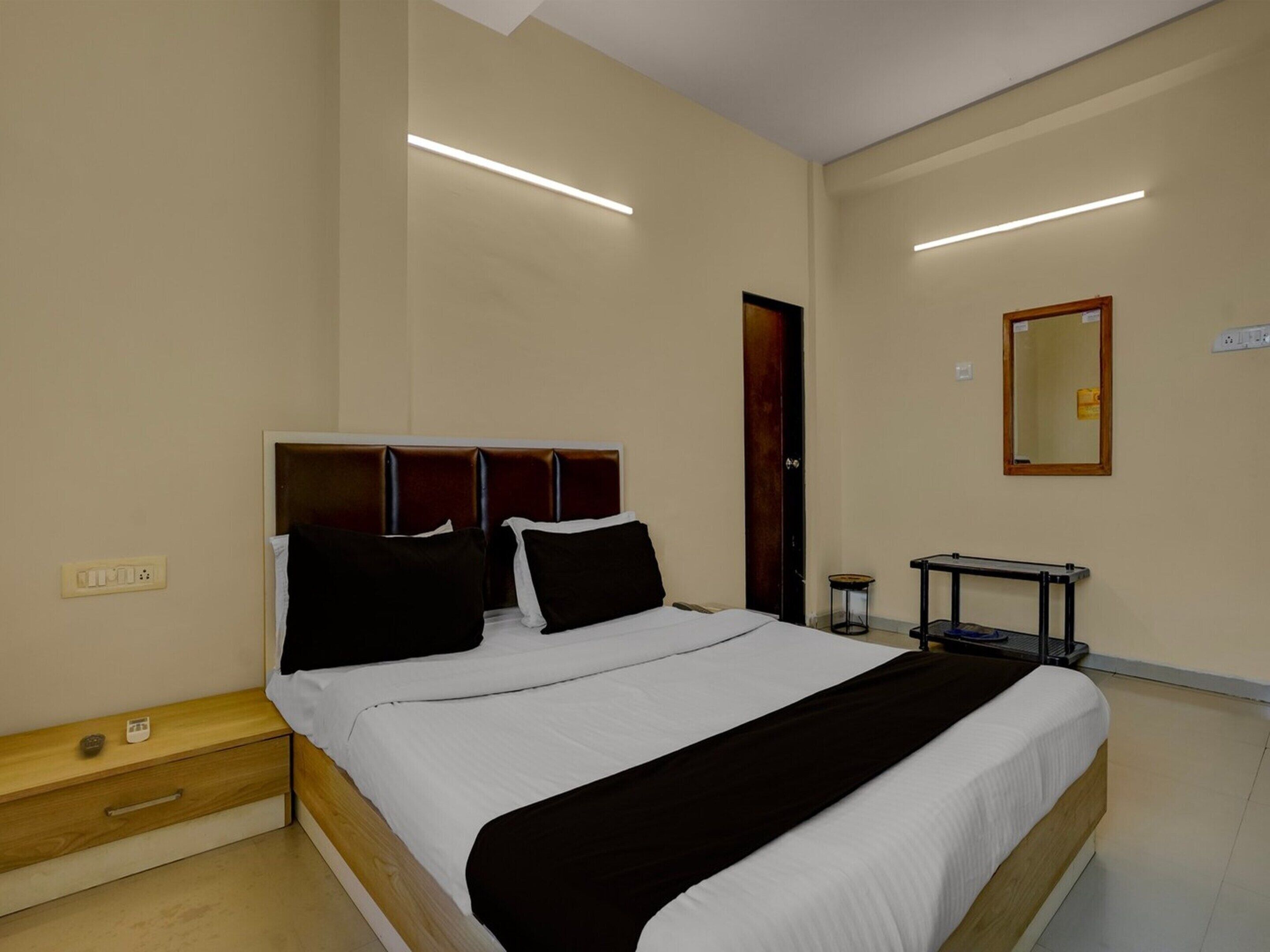 A hotel room with a bed, bedside table, nightstand, and a small table with a chair.