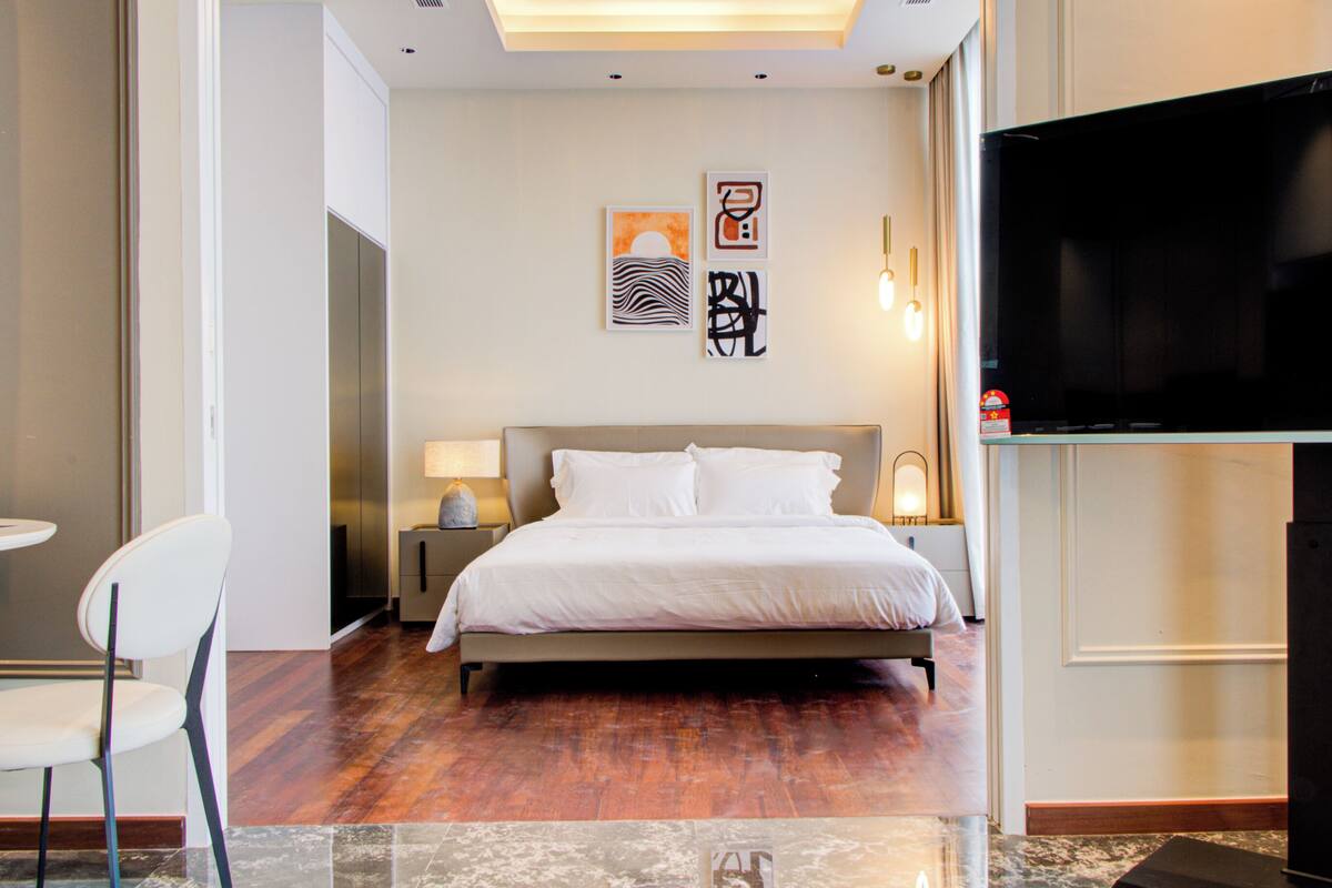 Een hotelkamer met een bed, een televisie, een stoel en kunst aan de muur.