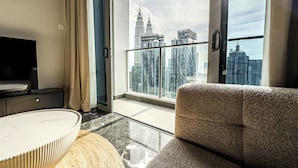 A modern living room with a sofa, a TV, and a large window with a city view. - Royce Residences KLCC by CREMES KL (Kuala Lumpur)