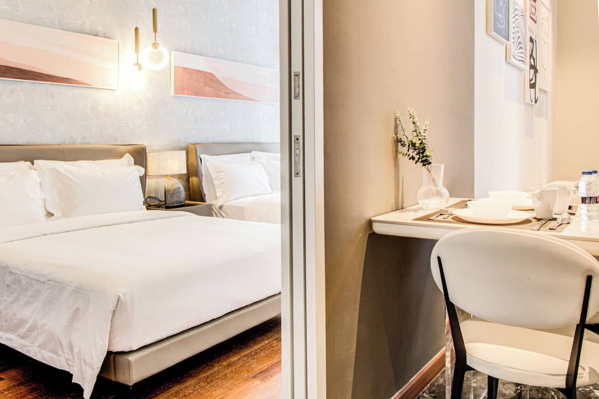 Een hotelkamer met een bed, nachtkastje, lamp en een kleine tafel met stoel.