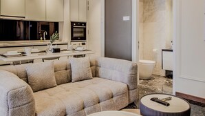 A modern living room with a sectional sofa, a dining table, and a kitchen area with appliances. - Royce Residences KLCC by CREMES KL (Kuala Lumpur)