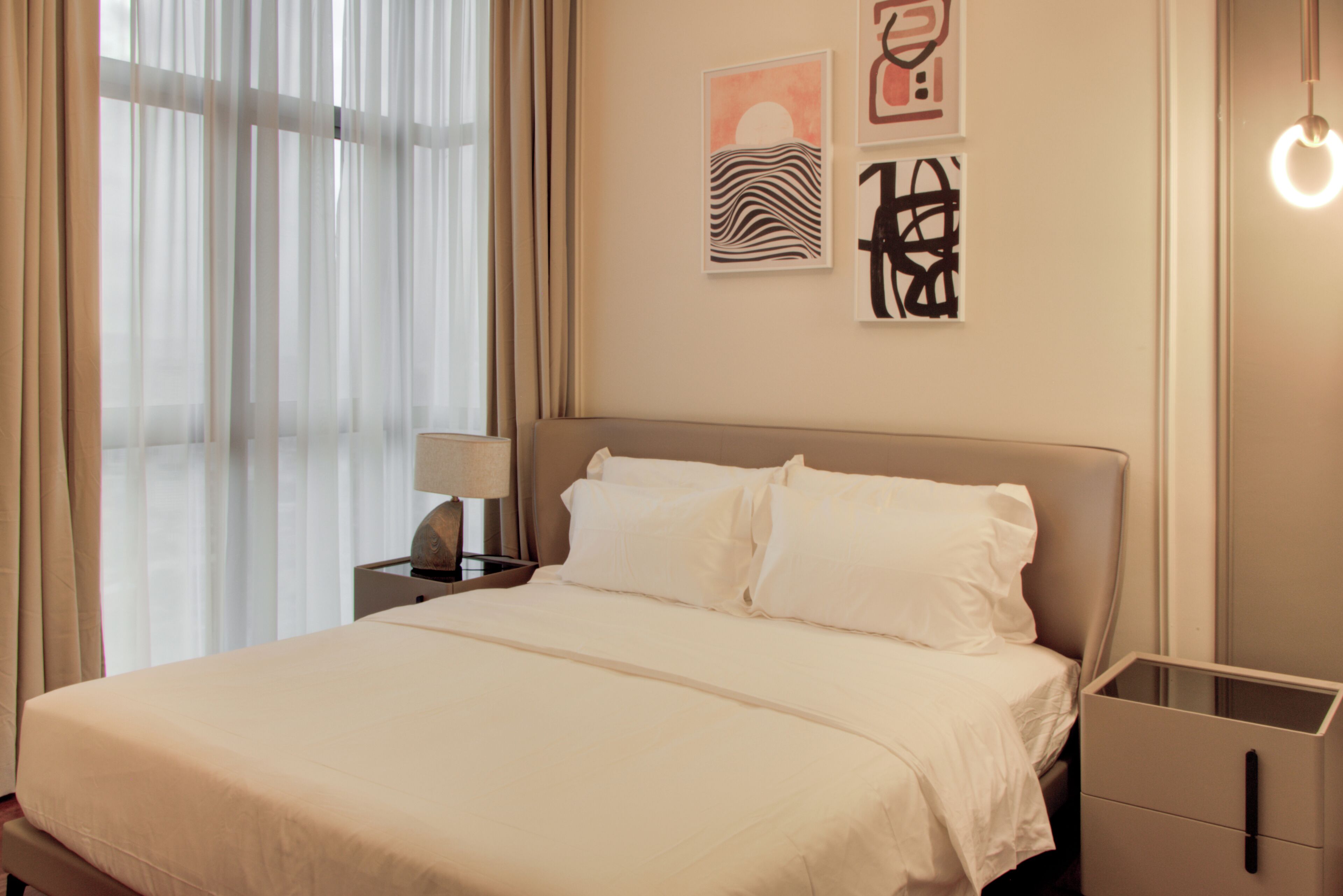 Een slaapkamer met een bed, nachtkastje, lamp en kunst aan de muur.