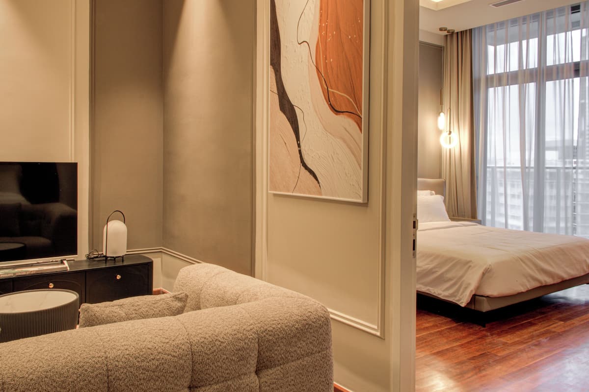 Een moderne hotelkamer met een bed, een zithoek, een flatscreen televisie en een groot abstract schilderij aan de muur.