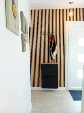 A hallway with a striped wall, a coat rack with a scarf, and a door.