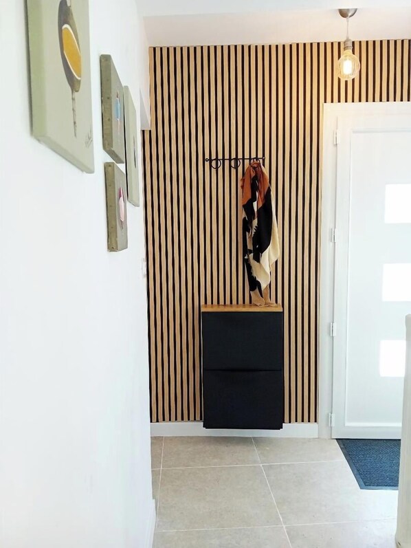 Ein Korridor mit einer gestreiften Wand, einem Kleiderhaken mit einem Schal und einer Tür.