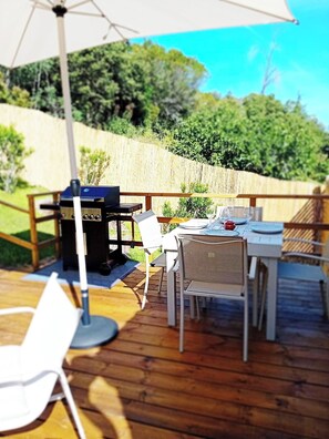 Terraza exterior con parrilla, sillas y mesa lista para comer.