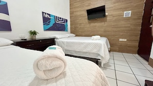 A hotel room with two beds, a TV, a painting, and a QR code on the wall.