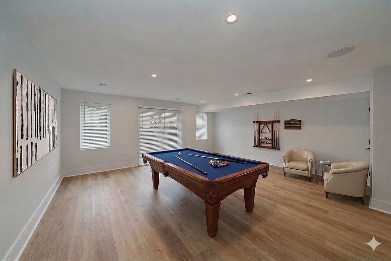 A spacious room with a pool table, two chairs, and a billiard rack.