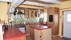 Cozinha com armários de madeira, bancada vermelha e forno embutido.