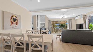 Ein modernes Wohnzimmer mit Essbereich, einem grauen Sofa und einem Deckenventilator.