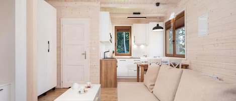 A modern interior with a wooden floor, a sofa, a dining table, and a kitchen area.