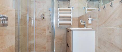 A modern bathroom with a glass-enclosed shower, a white toilet, and a sink with a mirror above it.
