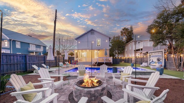 Un patio trasero con un brasero, mobiliario exterior y una piscina.