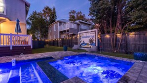 Un patio trasero con un jacuzzi, una terraza de madera, un cartel de St. Augustine y una casa con balcón.