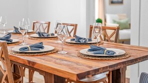 Una mesa de comedor de madera dispuesta con platos, servilletas y copas de vino.