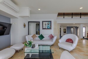 Ein modernes Wohnzimmer mit einem weißen Sofa, einem Glastisch und einem Fernseher.