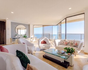 A modern living room with a glass coffee table, white sofas, and a view of the sea. - Ocean-View Triplex Penthouse: 4 Bedrooms (Cartagena de Indias)