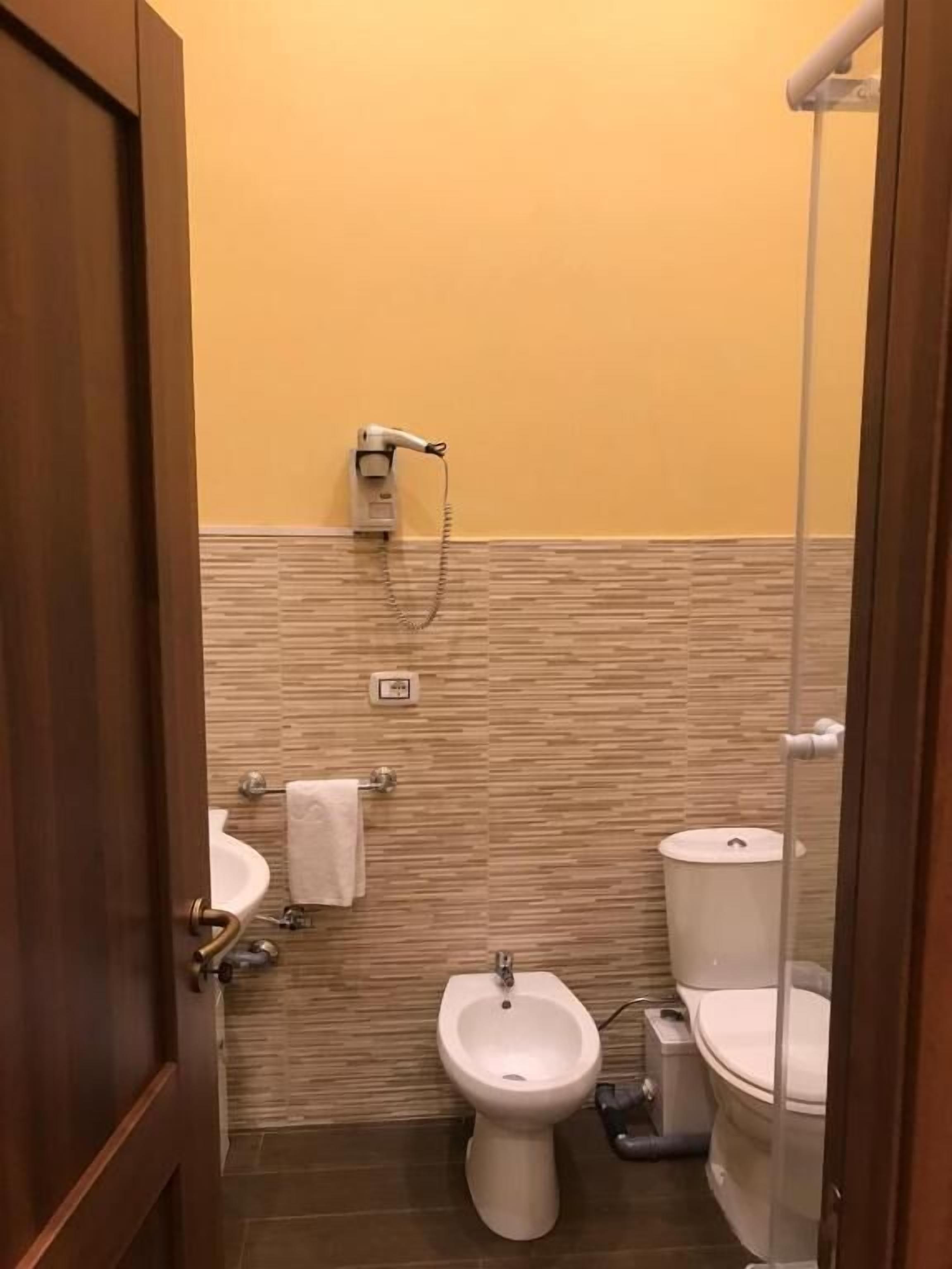 Une salle de bain équipée d’un bidet, de toilettes, d’un lavabo et d’un porte-serviettes.