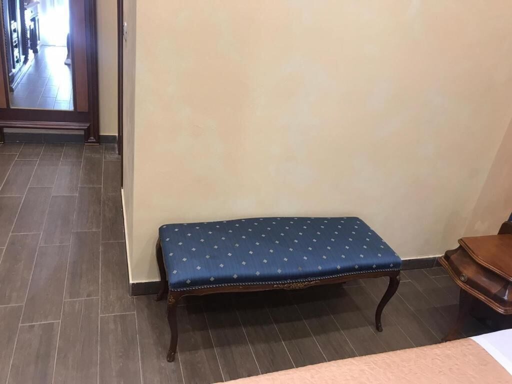 A room with a bench against a wall, a wooden table, and a tiled floor.