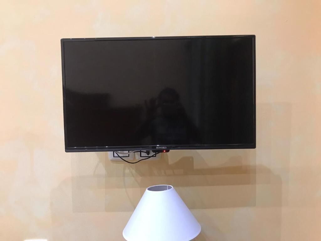 En platt-TV som är monterad på en vägg, med en vit lampa placerad under den.