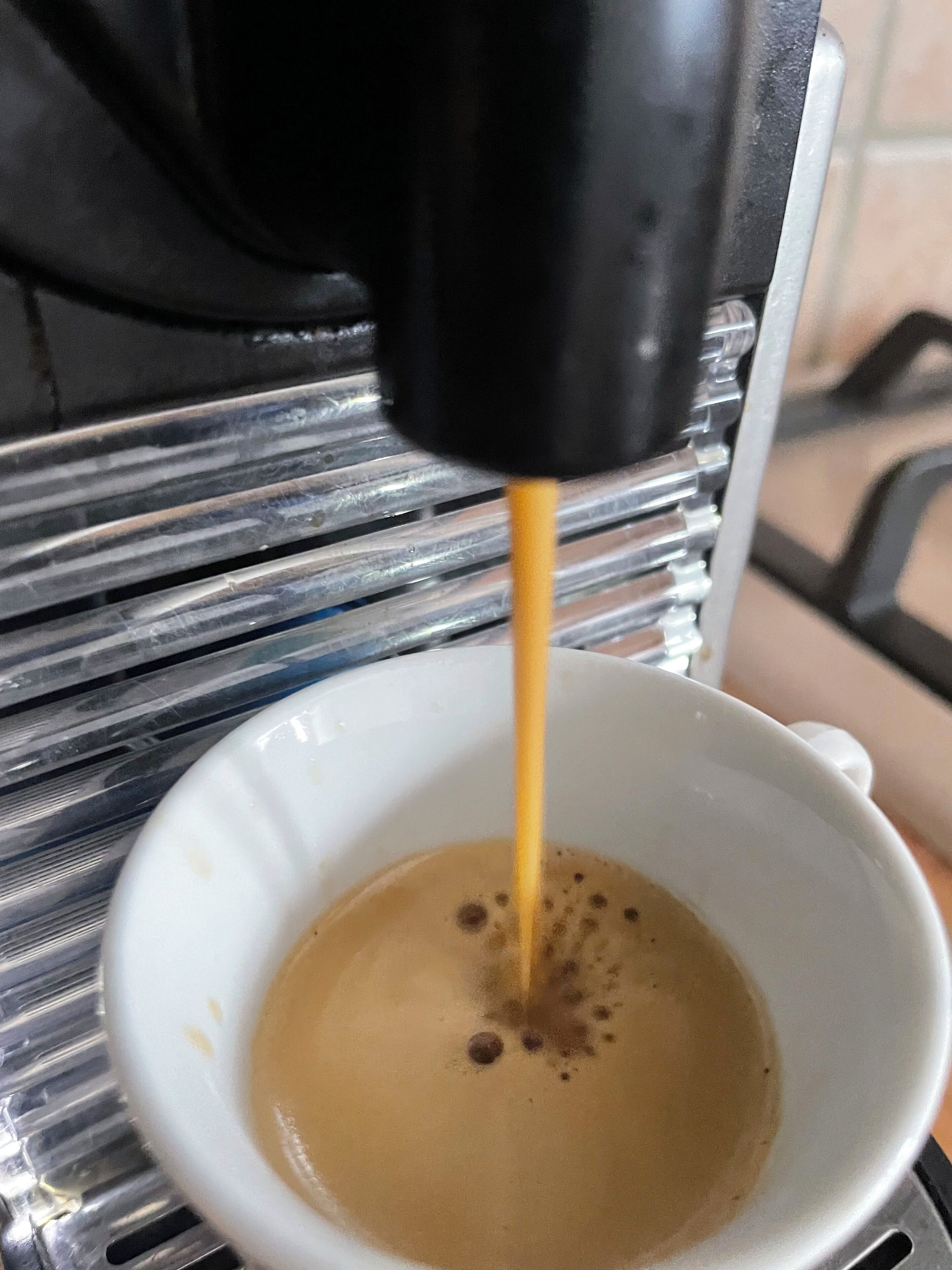 Eine Kaffeemaschine füllt Kaffee in eine weiße Tasse.