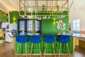 A modern kitchen with a green accent wall, bar stools, and a variety of decorative items. - Sea View Apt w/Pool & Near Jan Thiel Beach (Willemstad)