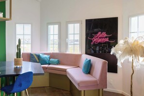 A modern living room with a pink sofa, a blue chair, a cactus, and a neon sign. - Sea View Apt w/Pool & Near Jan Thiel Beach (Willemstad)